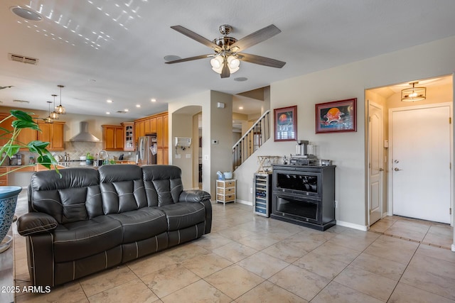 living room featuring stairway, visible vents, baseboards, light tile patterned flooring, and arched walkways