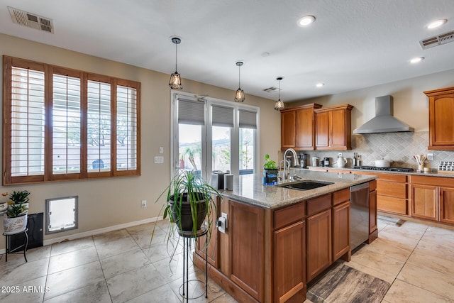 kitchen featuring visible vents, a sink, decorative backsplash, appliances with stainless steel finishes, and wall chimney exhaust hood