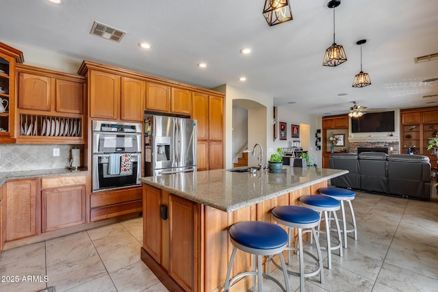 kitchen featuring a sink, stainless steel appliances, light stone counters, and visible vents