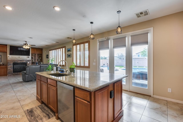 kitchen with visible vents, dishwasher, a stone fireplace, brown cabinets, and a sink