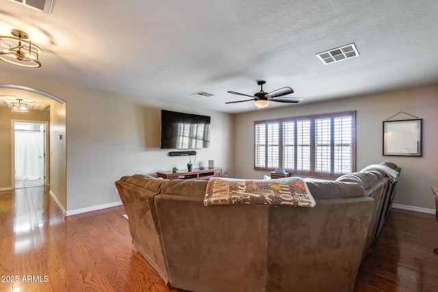 living area featuring visible vents, arched walkways, and wood finished floors