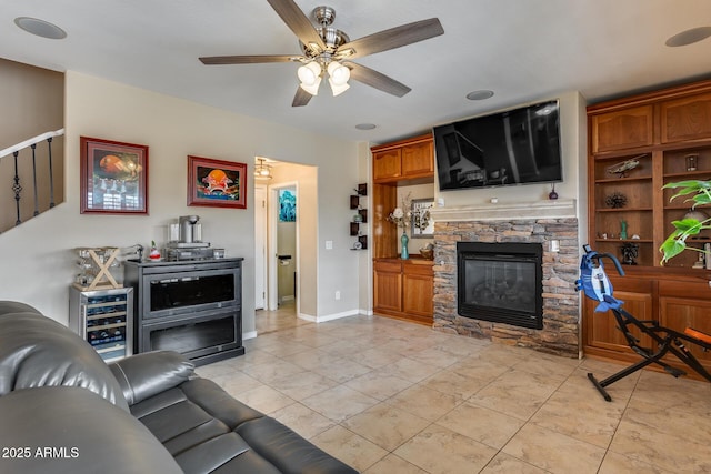 living area with light tile patterned floors, baseboards, a fireplace, ceiling fan, and wine cooler