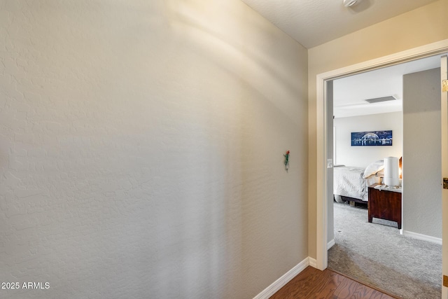 hall with wood finished floors, baseboards, and visible vents