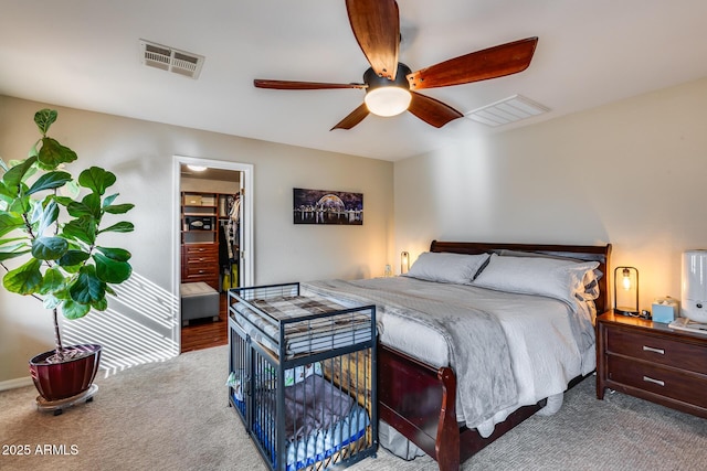 bedroom with a walk in closet, carpet, visible vents, and a ceiling fan