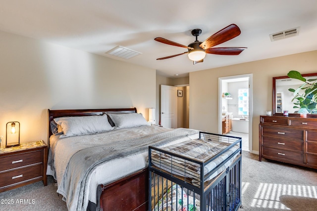 carpeted bedroom with visible vents, ensuite bath, and ceiling fan