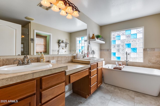 bathroom featuring visible vents, double vanity, a shower with shower door, a soaking tub, and a sink