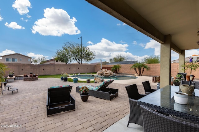 view of patio / terrace featuring outdoor dining space, a fenced in pool, a fire pit, and a fenced backyard