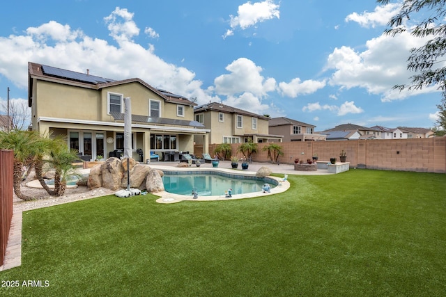 back of property featuring a patio, solar panels, a fenced backyard, stucco siding, and a lawn