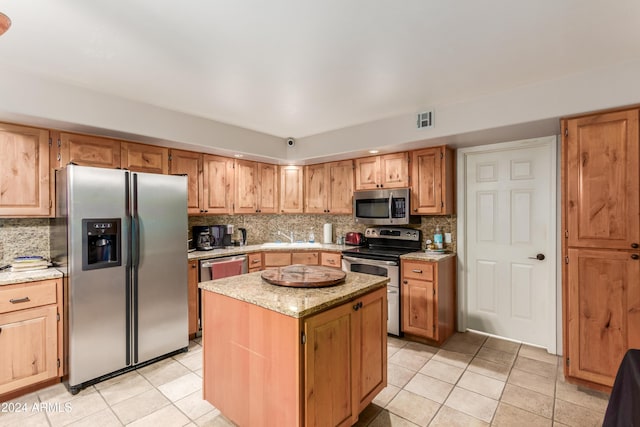 47012 N New River Rd, New River, AZ 85087 - kitchen featuring stainless steel appliances, light tile patterned floors, tasteful backsplash, a center island, and light stone countertops