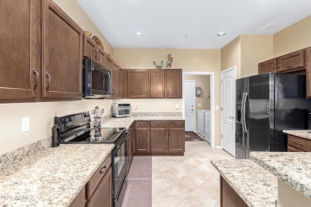 kitchen with light stone countertops, independent washer and dryer, and black appliances