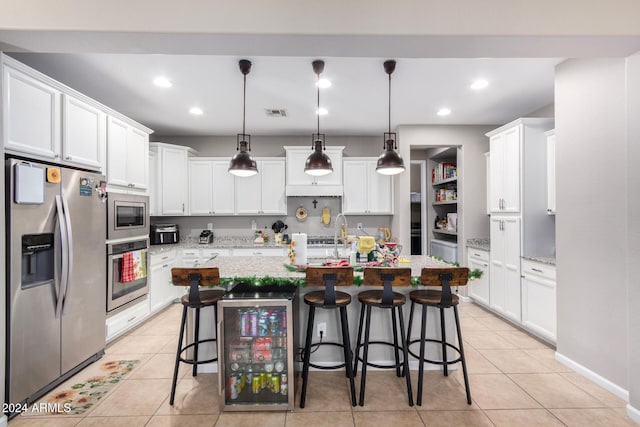 kitchen featuring appliances with stainless steel finishes, a kitchen breakfast bar, light stone counters, beverage cooler, and pendant lighting