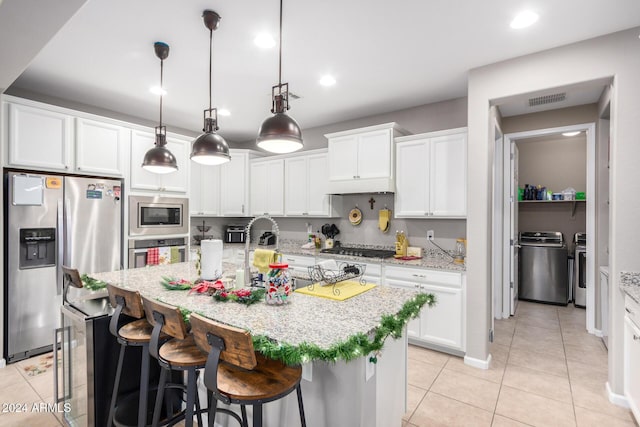 kitchen featuring pendant lighting, stainless steel appliances, white cabinetry, and an island with sink