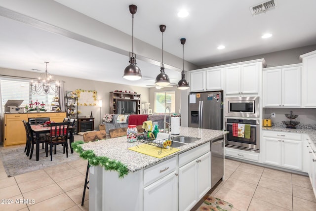 kitchen featuring white cabinets, ceiling fan with notable chandelier, an island with sink, decorative light fixtures, and stainless steel appliances