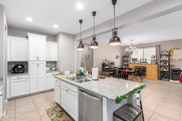 kitchen with stainless steel dishwasher, white cabinets, sink, and an island with sink