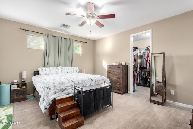 bedroom with a walk in closet, ceiling fan, a closet, and light hardwood / wood-style flooring