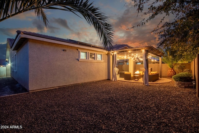 back house at dusk featuring an outdoor hangout area