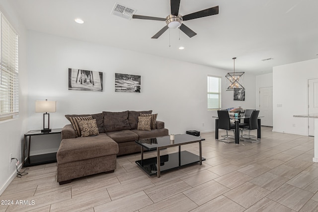 living room with ceiling fan with notable chandelier