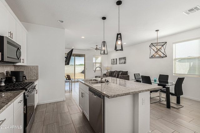 kitchen featuring appliances with stainless steel finishes, sink, pendant lighting, white cabinets, and a center island with sink