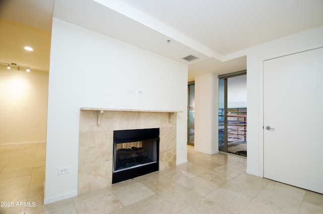 unfurnished living room featuring rail lighting and a tile fireplace