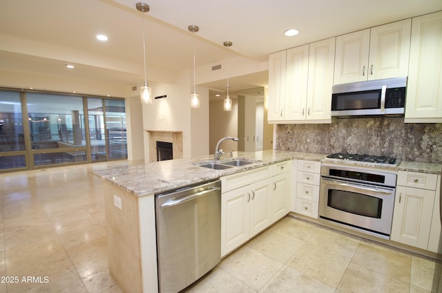 kitchen with decorative light fixtures, sink, light stone counters, kitchen peninsula, and stainless steel appliances