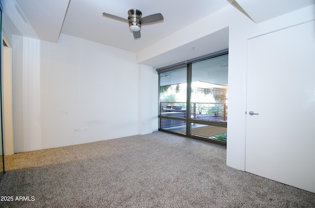 empty room featuring expansive windows, ceiling fan, and carpet floors