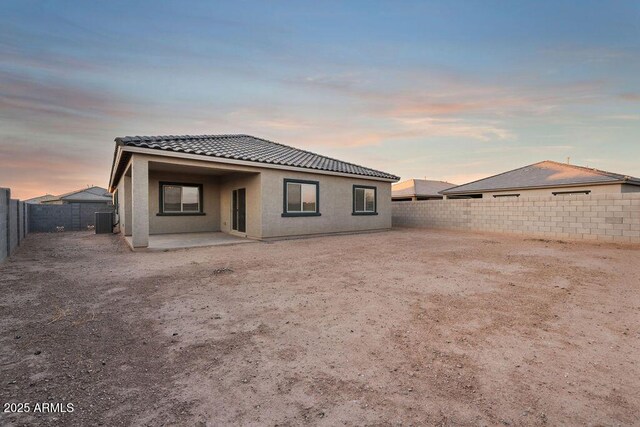 43637 W Cypress Ln, Maricopa, AZ 85138 - back of property at dusk with a patio, a tile roof, central AC, and a fenced backyard