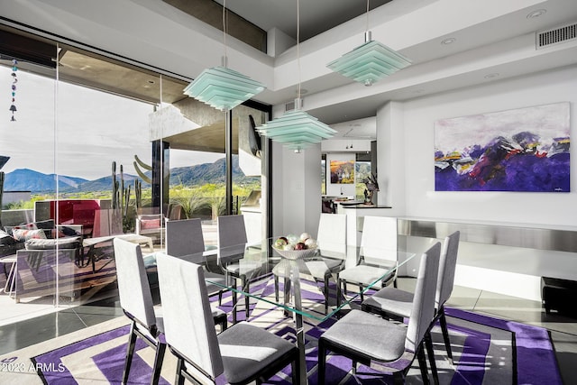 dining area featuring tile patterned floors, a mountain view, and a towering ceiling