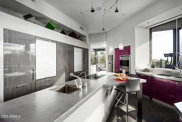 kitchen with pendant lighting, black electric stovetop, stainless steel counters, and sink