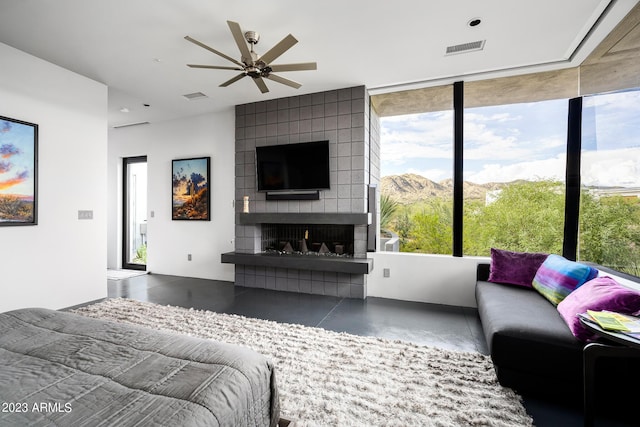 bedroom featuring multiple windows, ceiling fan, a fireplace, and concrete floors