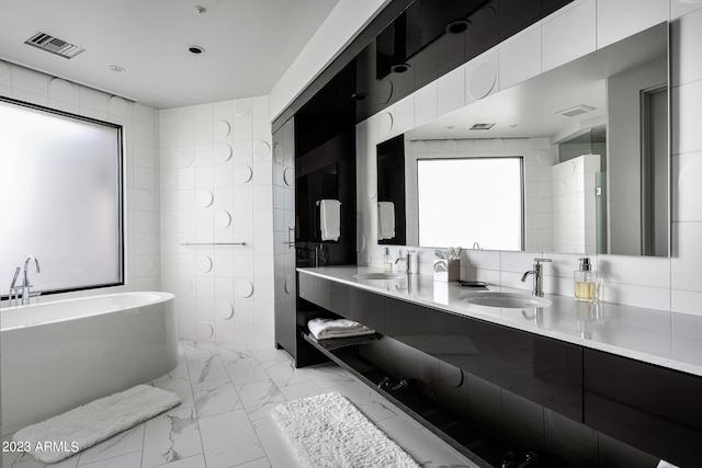 bathroom featuring a tub, vanity, and tile walls