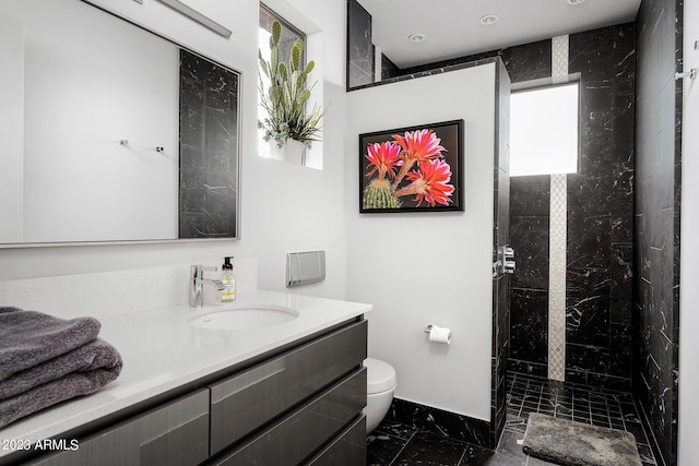 bathroom with vanity, toilet, and tiled shower