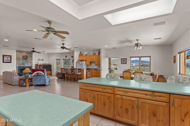 22900 W Hylton Way, Congress, AZ 85332 - kitchen featuring white refrigerator, light tile patterned floors, a tile fireplace, ceiling fan, and a kitchen island