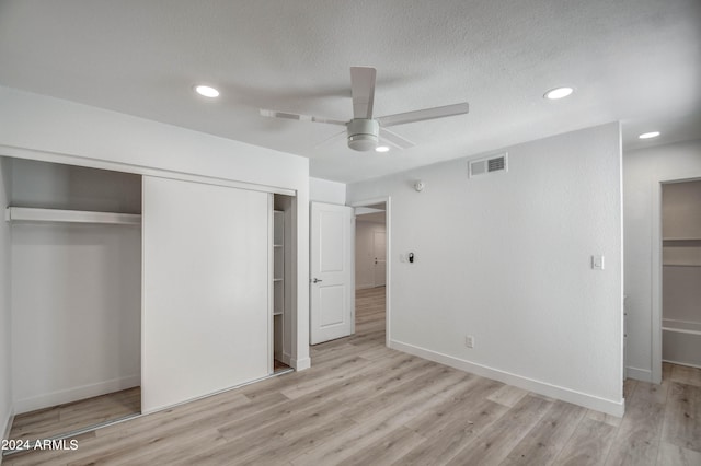 unfurnished bedroom featuring light hardwood / wood-style floors, ceiling fan, and a closet