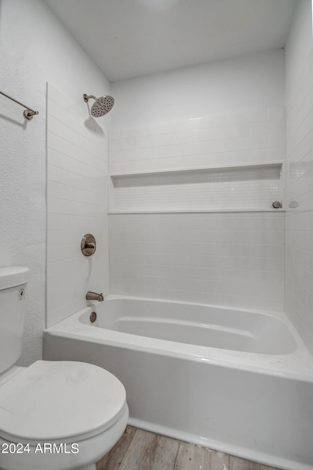 bathroom featuring tiled shower / bath combo, hardwood / wood-style flooring, and toilet