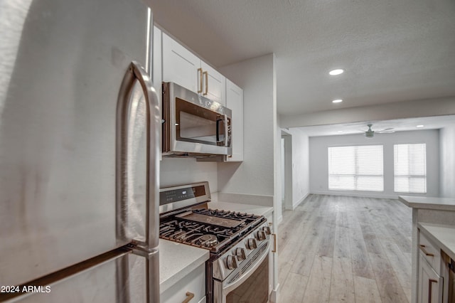 kitchen with light hardwood / wood-style floors, ceiling fan, stainless steel appliances, and white cabinets