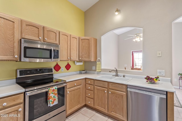 kitchen with lofted ceiling, sink, light tile patterned floors, appliances with stainless steel finishes, and kitchen peninsula