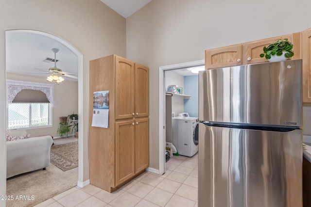 kitchen with light tile patterned floors, stainless steel fridge, washer / clothes dryer, and light brown cabinets