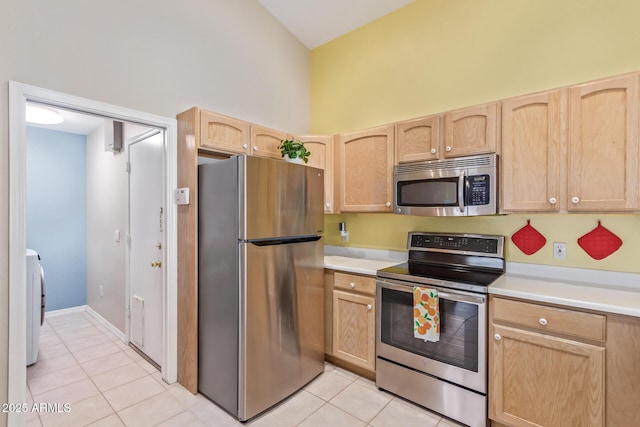 kitchen with light brown cabinetry, light tile patterned floors, stainless steel appliances, and a high ceiling