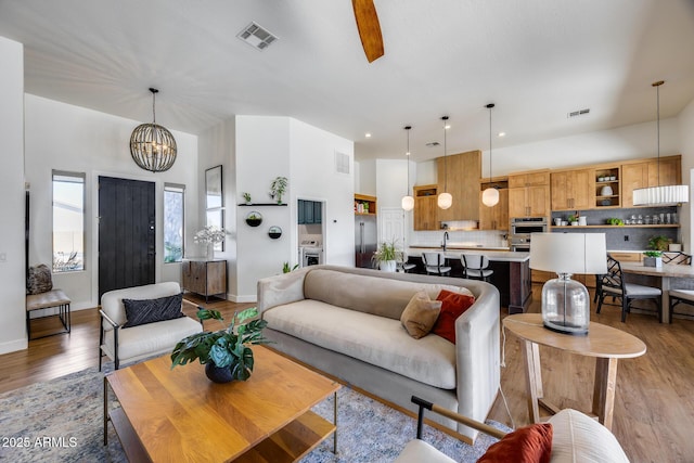 living area with light wood-style floors, visible vents, and a chandelier