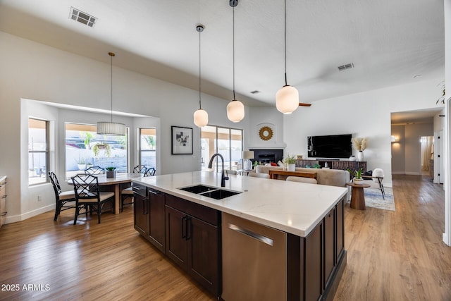 kitchen featuring visible vents, light wood-style flooring, a sink, dark brown cabinets, and dishwasher