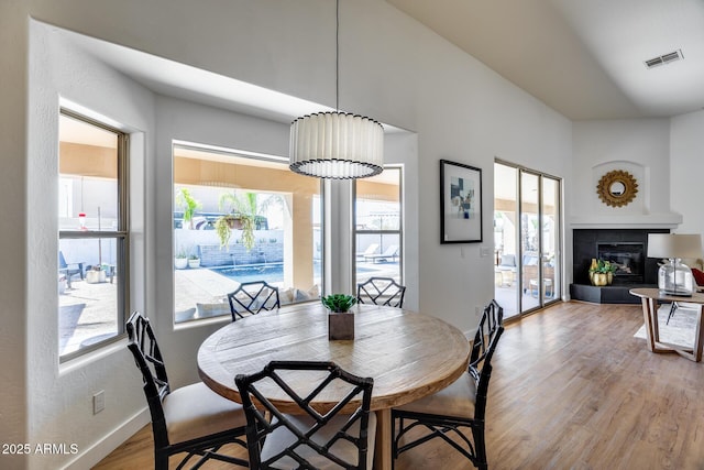 dining room with visible vents, a fireplace, baseboards, and light wood-style floors