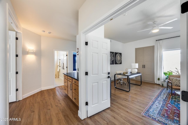 corridor with light wood-style flooring and baseboards