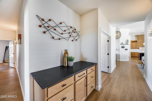 hall with baseboards and light wood-style floors