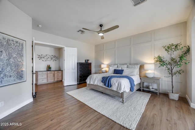 bedroom featuring a decorative wall, baseboards, light wood-type flooring, and visible vents