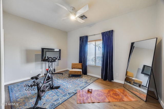 exercise area featuring wood finished floors, a ceiling fan, visible vents, and baseboards