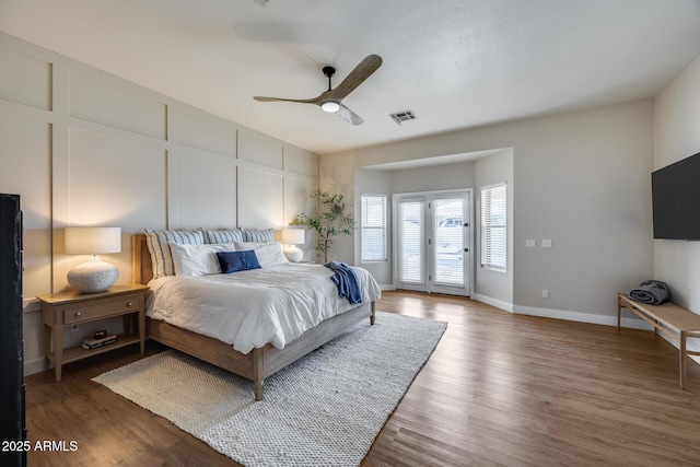 bedroom featuring visible vents, access to outside, wood finished floors, and a decorative wall