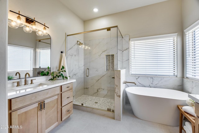 bathroom featuring recessed lighting, a marble finish shower, a freestanding bath, and vanity