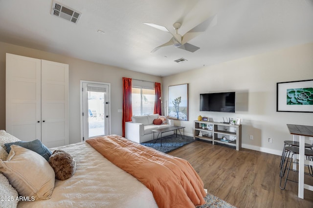 bedroom featuring a ceiling fan, wood finished floors, visible vents, and baseboards