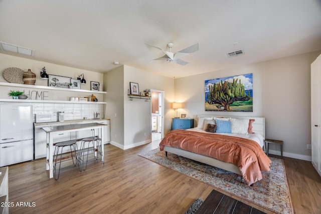 bedroom featuring visible vents, a sink, baseboards, and wood finished floors