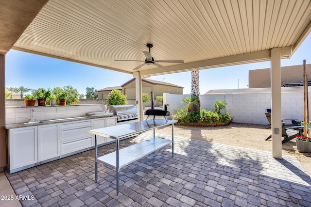 view of patio with area for grilling, ceiling fan, a fenced backyard, and a sink